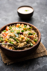 Broken wheat or Daliya Upma, served in a bowl. selective focus