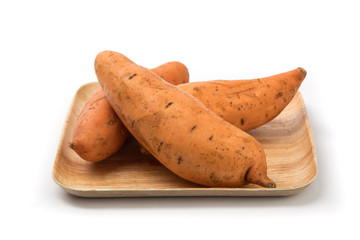 a pile of sweet potatoes on a wooden bamboo plate isolated on white