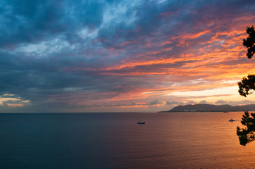 Fototapeta premium Red and blue sunset over sea with boat