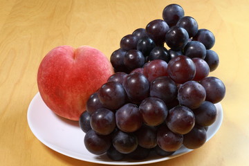 Peaches and black grapes on the white plate