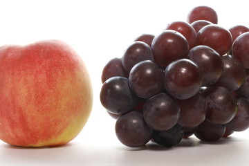 Peaches and black grapes on white background