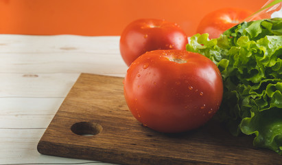 Lettuce and a ripe red tomato on a chopping Board. Fresh fruit