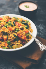 Broken wheat or Daliya Upma, served in a bowl. selective focus