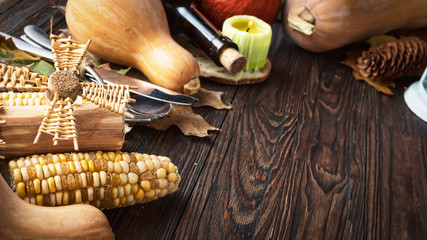 Happy Thanksgiving Day background, wooden table decorated with pumpkins, wine, corncob, candles and autumn leaves. The concept of harvest and autumn celebration.