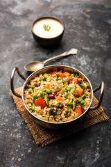 Broken wheat or Daliya Upma, served in a bowl. selective focus