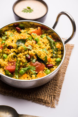 Broken wheat or Daliya Upma, served in a bowl. selective focus