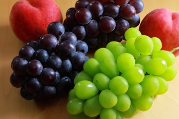 Black grape, green grape and peaches on the table