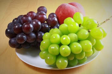 Black grape, green grape and peach on the table