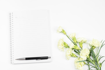 Blank notebook with pen and white carnation flower on white background, top view