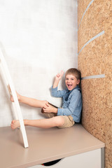 A little boy is playing the tablet in various poses alone at his room