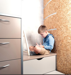 A little boy is playing the tablet in various poses alone at his room