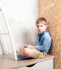 A little boy is playing the tablet in various poses alone at his room