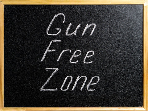 Inscription Gun Free Zone in chalk on a school blackboard