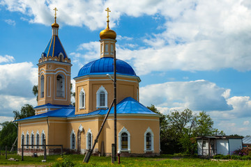 Fototapeta na wymiar Yellow Orthodox Church with blue domes on a background of blue sky with white clouds