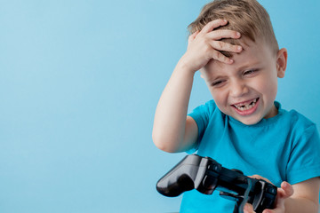 Little kid boy 2-3 years old wearing blue clothes hold in hand joystick for gameson blue background children studio portrait. People childhood lifestyle concept. Mock up copy space