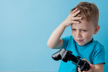 Little kid boy 2-3 years old wearing blue clothes hold in hand joystick for gameson blue background children studio portrait. People childhood lifestyle concept. Mock up copy space