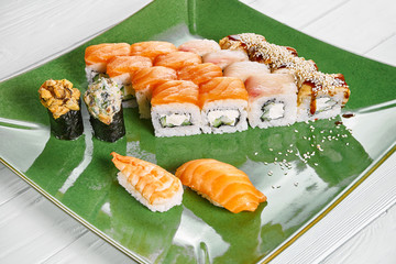 Close up view on set of assorted roll and sushi on green plate isolated on white wooden background. Sushi with salmon, eel. japanese sushi food