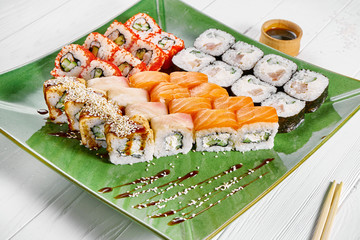 Close up view on set of assorted roll and sushi on green plate isolated on white wooden background. Sushi with salmon, eel. japanese sushi food