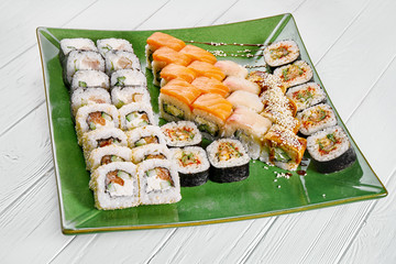 Close up view on set of assorted roll and sushi on green plate isolated on white wooden background. Sushi with salmon, eel. japanese sushi food