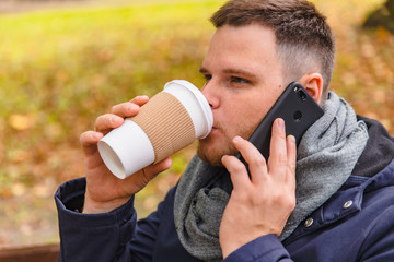 man drinking coffee outdoors autumn season talking on the phone
