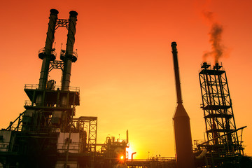 Smoke stacks of petrochemical industrial on orange sky sunset background, Oil and gas industrial...