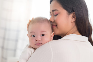 Young Asian mother holding her baby kid with love.