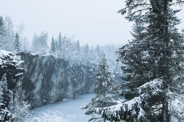Winter Karelian forest, spruce trees in the snow and the river, gloomy sky. The river in the Karelian reserve among the snowy firs.