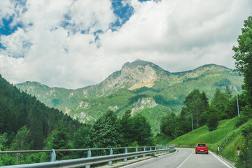 small red car on the road through mountains road trip