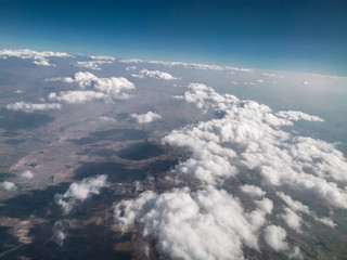 Naklejka premium puffy clouds and earth view from above through airplane window