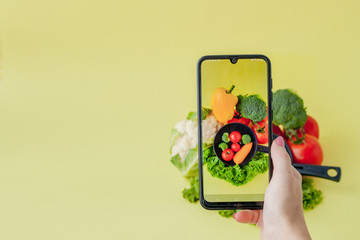 Girl taking picture of vegetarian food on table with her smartphone. Vegan and healthy concept.