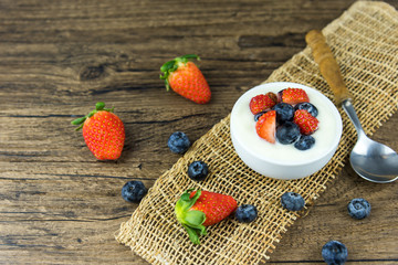 Bowl of homemade granola with Greek yogurt and fresh berries mix on wooden background from top view. Healthy blueberry and Strawberry parfait in a jar.