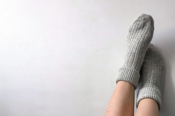 Women wearing grey knitted cozy socks on gray background. Сopyspace for text 