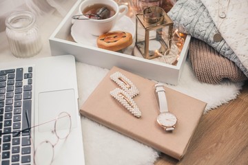 Toned photo. Autumn decor. A laptop, a mug of hot tea, a bun, candles. Cozy. Autumn.