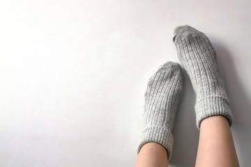 Women wearing grey knitted cozy socks on gray background. Сopyspace for text 