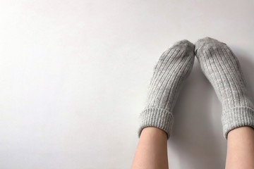 Women wearing grey knitted cozy socks on gray background. Сopyspace for text 