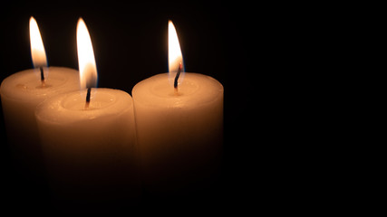 Burning candles on a black background with space to put any text