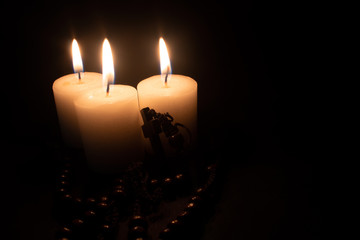 Rosary to pray with candles lit around, black background