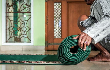 A man rolling praying rug at a mosque.