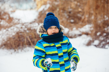 Fototapeta na wymiar little boy playing with snow. making snowballs.