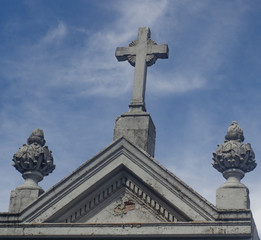 old stone cross on church roof blue sky