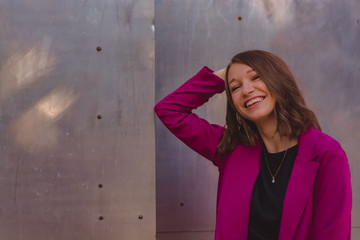 A girl in trendy plum and bright suit walks around the city and has fun. Style.