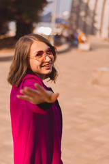 A girl in trendy plum and bright suit walks around the city and has fun. Style.