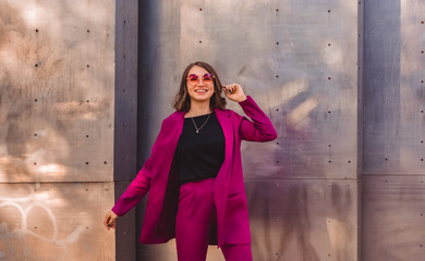 A girl in trendy plum and bright suit walks around the city and has fun. Style.