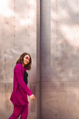 A girl in trendy plum and bright suit walks around the city and has fun. Style.