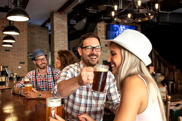 Two couple sitting in beer house and having fun