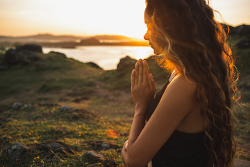 Woman praying alone at sunrise. Nature background. Spiritual and emotional concept. Sensitivity to nature - 293186929