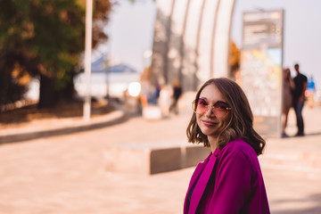 A girl in trendy plum and bright suit walks around the city and has fun. Style.