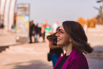 A girl in trendy plum and bright suit walks around the city and has fun. Style.