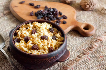 Sweet millet porridge with dark raisins in ceramic rustic bowl