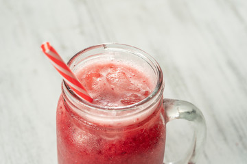 Fresh organic red smoothie in glass mug on white table, close up. Refreshing summer fruit drink. The concept of healthy eating. Cranberry and raspberry smoothie